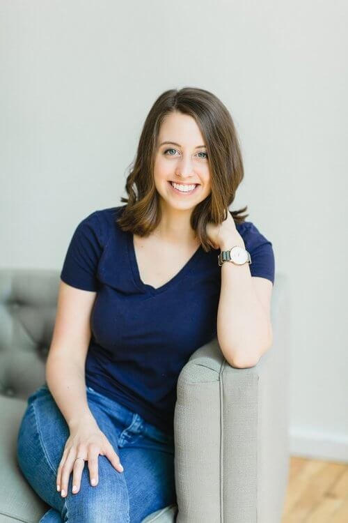 Photo of a Duett Client - Alexa Peduzzi of Food Blogger Pro and the Food Blogger Pro podcast - sitting on a grey couch wearing a blue shirt and denim jeans, smiling at the camera relaxed and happy