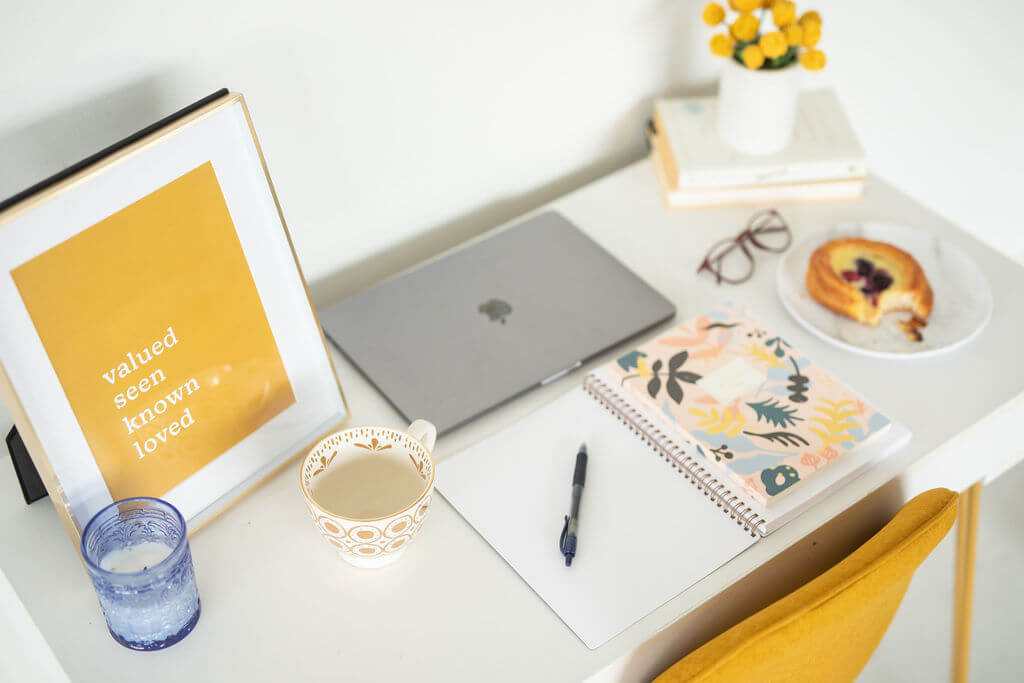 Desk with a laptop, coffee and a book about 6 practical ways to provide value with a nurture sequence